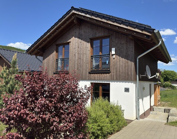Ett trähus med ett sluttande tak, stora fönster och en satellitantenn.