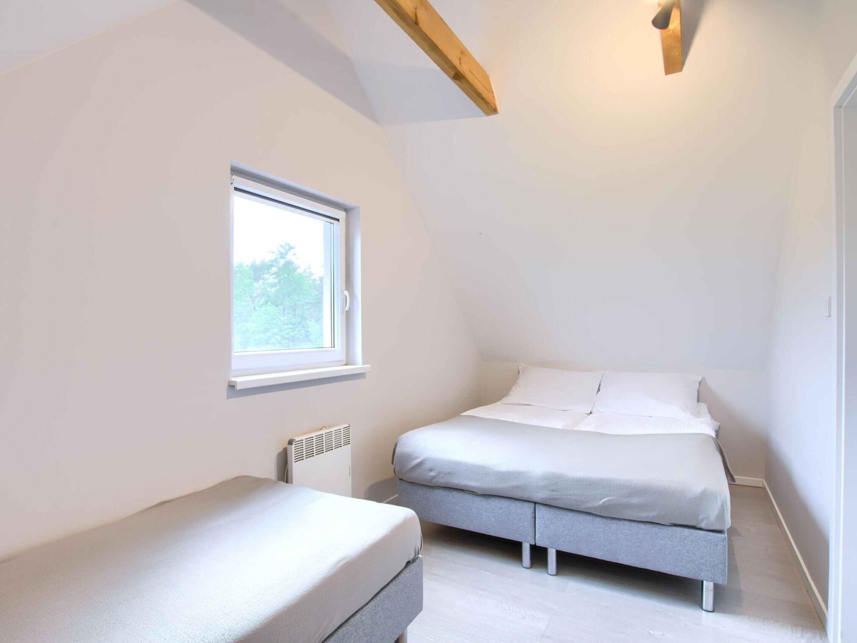 A small, well-lit bedroom with a single bed, a window, and a radiator.