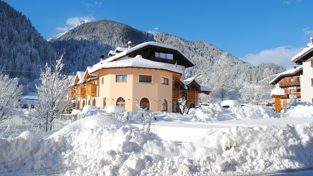 A snow-covered mountain lodge with a large central building and smaller structures. - Apartments Casa Caritro, Cusiano di Ossana (Ossana)