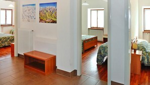 A room with two beds, a wooden bench, a radiator, and two paintings on the wall. - Apartments Casa Caritro, Cusiano di Ossana (Ossana)