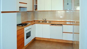 A compact kitchen with white cabinets, a stove, a sink, and a dishwasher. - Apartments Casa Caritro, Cusiano di Ossana (Ossana)