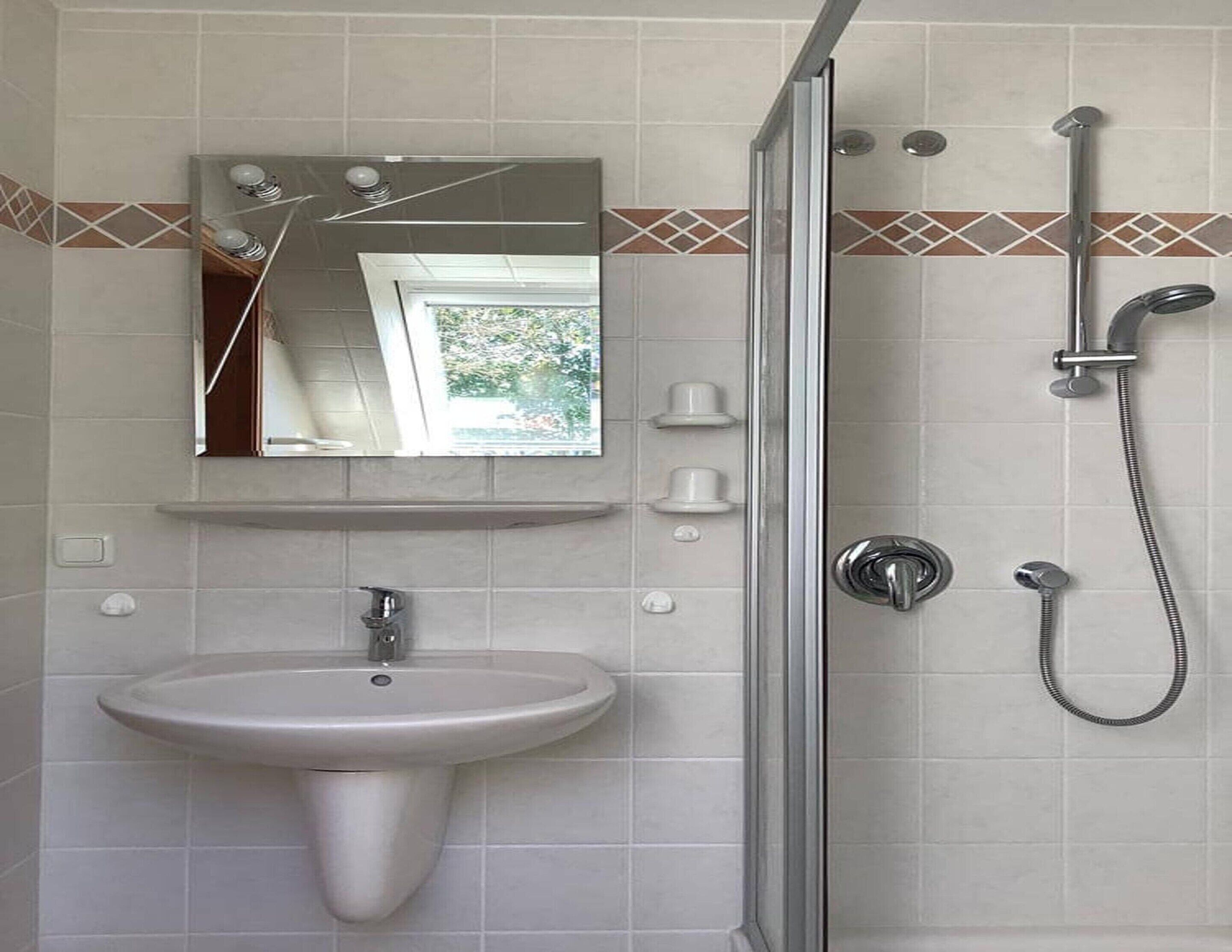 A bathroom with a sink, mirror, and shower.