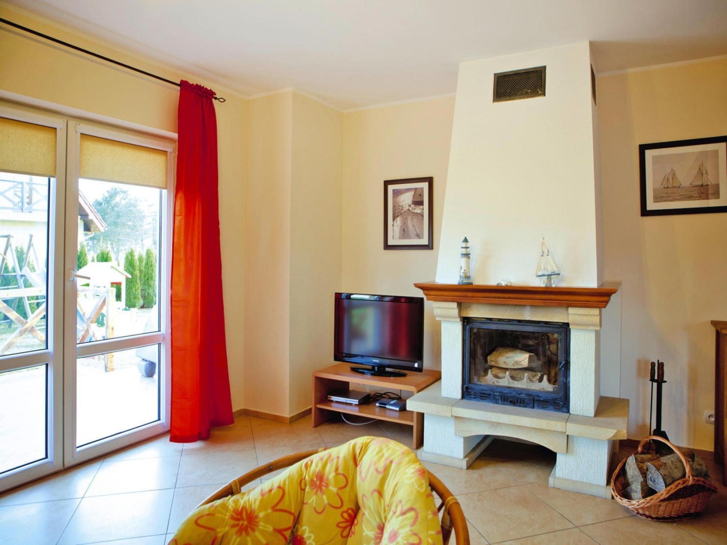 A living room with a fireplace, television, and a large sliding glass door leading to an outdoor area.