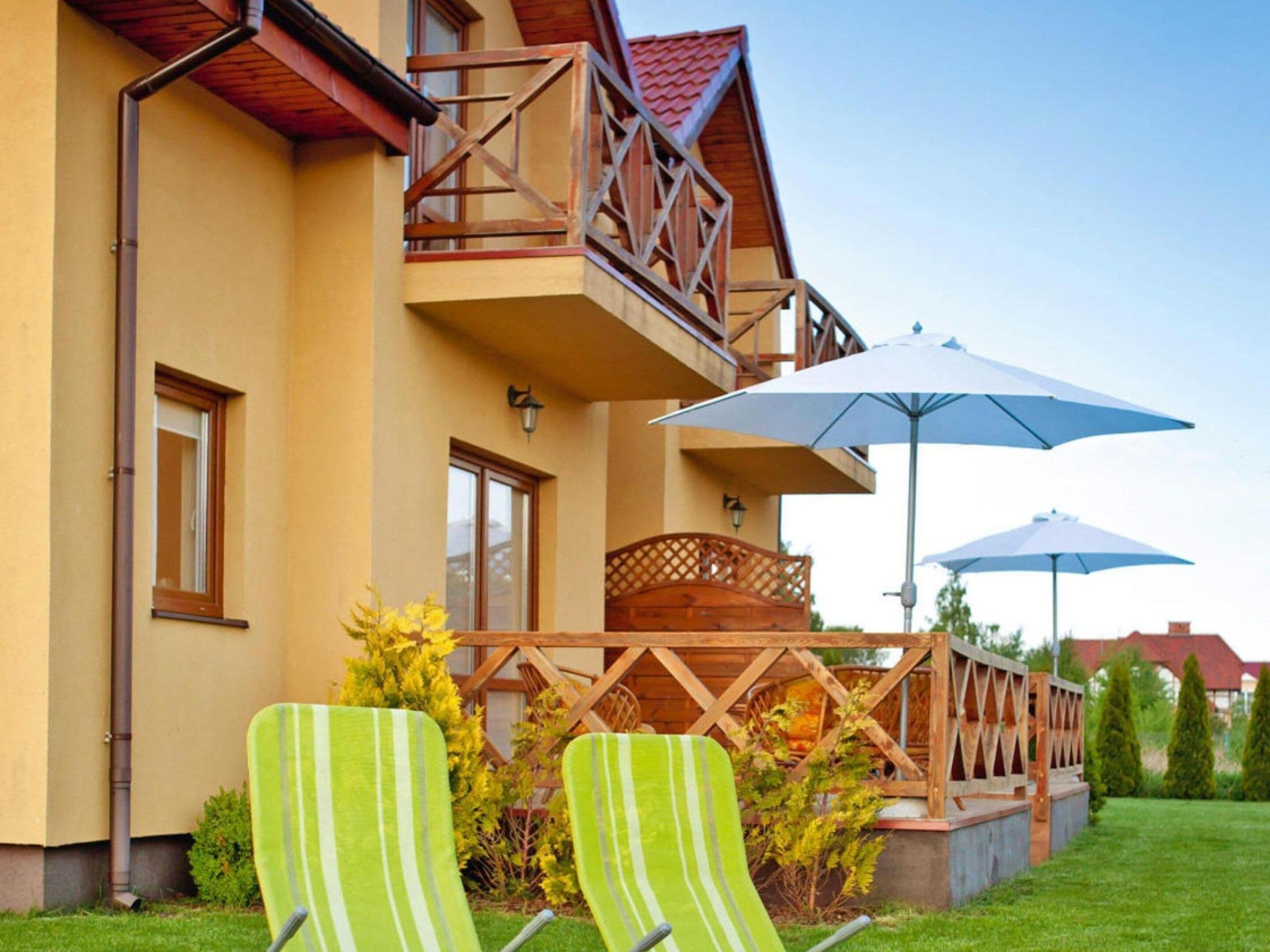 A two-story building with a balcony, outdoor seating, and umbrellas.