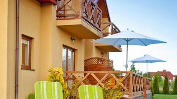 A two-story building with a balcony, outdoor seating, and umbrellas.