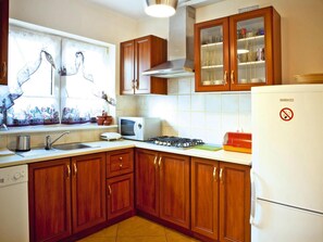 A kitchen with wooden cabinets, a microwave, a stove, and a refrigerator. - Half of Holiday Home, Terrace, Playground (Ustka)