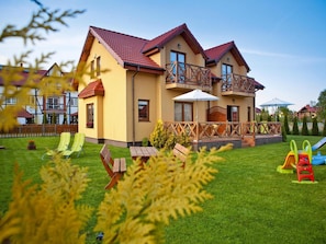 A two-story house with a balcony, a lawn, and outdoor furniture. - Half of Holiday Home, Terrace, Playground (Ustka)