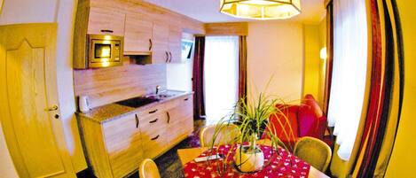 Una cocina funcional con microondas, armarios de madera y una mesa de comedor con sillas.
