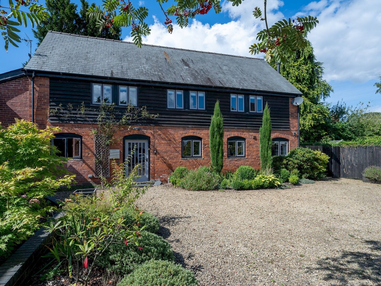 A two-story brick house with a gravel driveway and a well-maintained garden.
