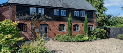 A two-story brick house with a gravel driveway and a well-maintained garden.