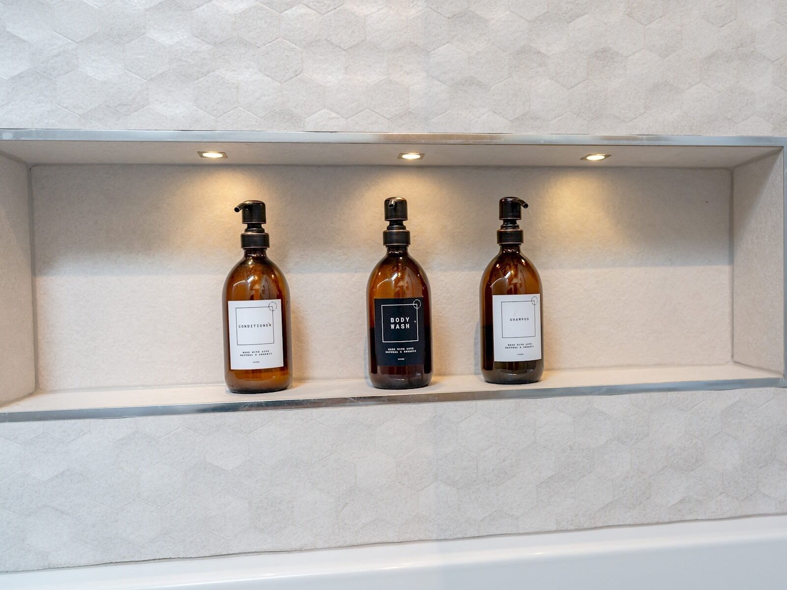 Three bottles of body wash and conditioner on a shelf.