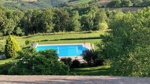 A swimming pool surrounded by lush greenery and a hilly landscape. - Tente Glamping Dans le Calme, Avec Piscine, Salle de Bain et Cuisine (Crespin)