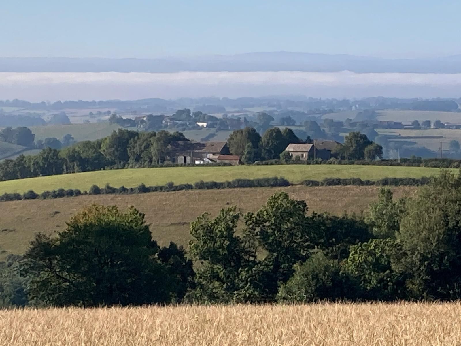 Un paisaje rural con colinas ondulantes, casas dispersas y campos.