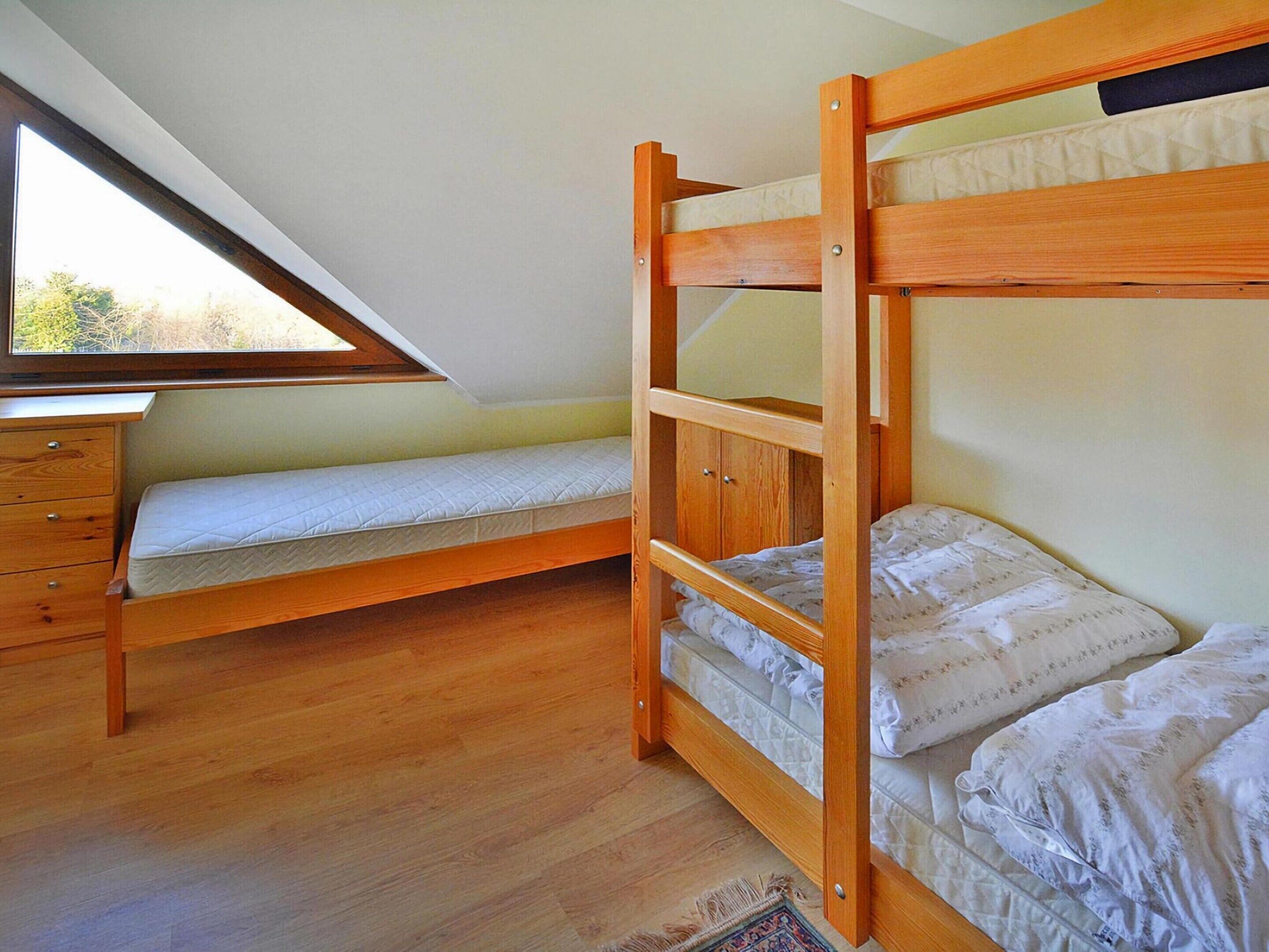 A dorm-style room with a bunk bed, a desk, and a dresser.