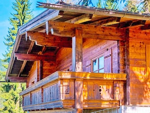 A wooden cabin with a balcony, large windows, and a sloped roof. - Chalet in Eben With Panoramic Mountain Views (Eben im Pongau)
