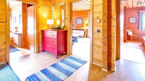 A wooden cabin interior with a red dresser, a mirror, a bed, and a bathroom visible through an open door. - Chalet in Eben With Panoramic Mountain Views (Eben im Pongau)
