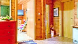 A wooden interior with a TV, a red dresser, a chair, and a star decoration. - Chalet in Eben With Panoramic Mountain Views (Eben im Pongau)