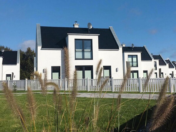 En moderne boligbygning med fladt tag, store vinduer og hvid facade.