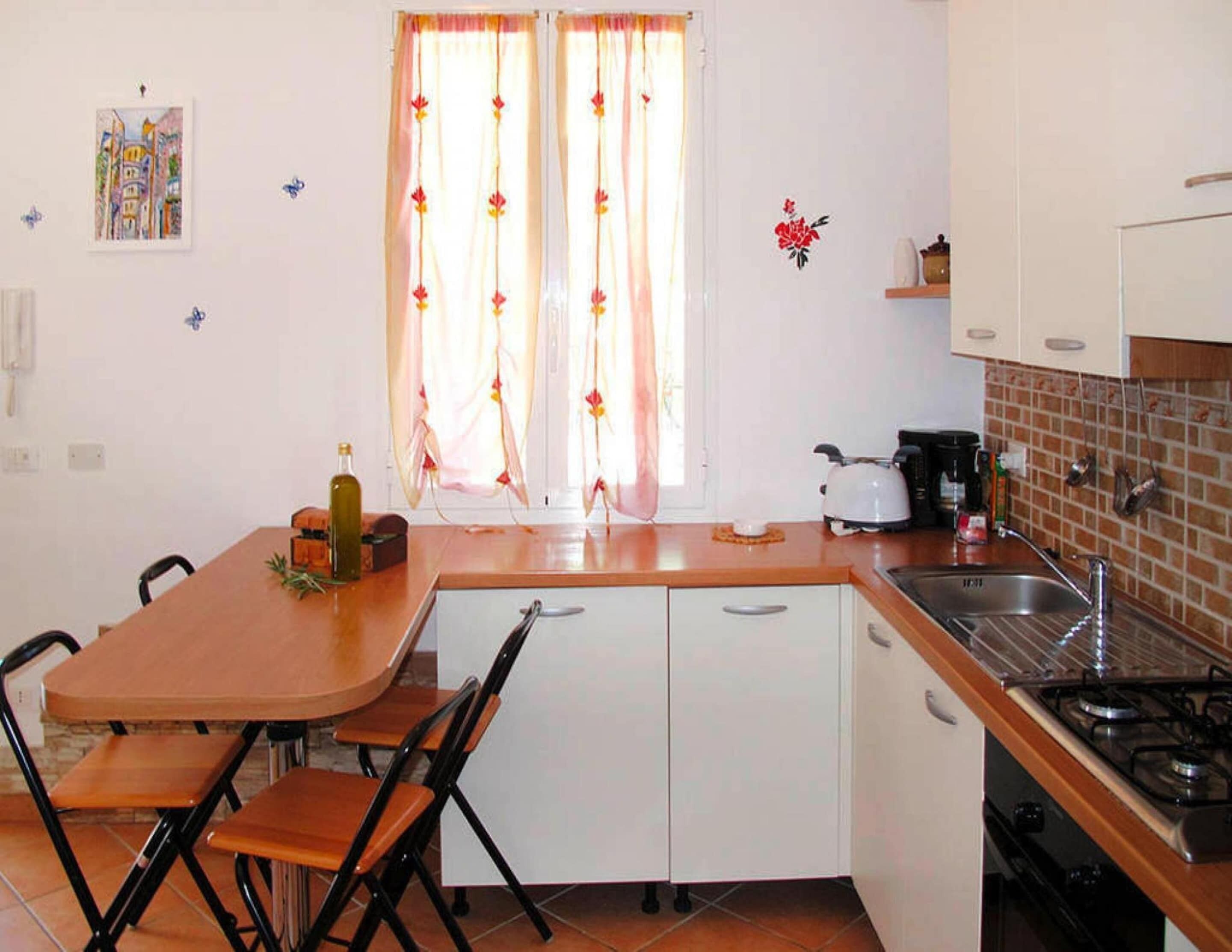 A compact kitchen with a dining area, including a table, chairs, and a stove.