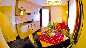 A compact kitchen with a microwave, wooden cabinets, and a dining table with chairs. - Apartment in Val Gardena Near Ski Slopes (Santa Cristina Val Gardena)