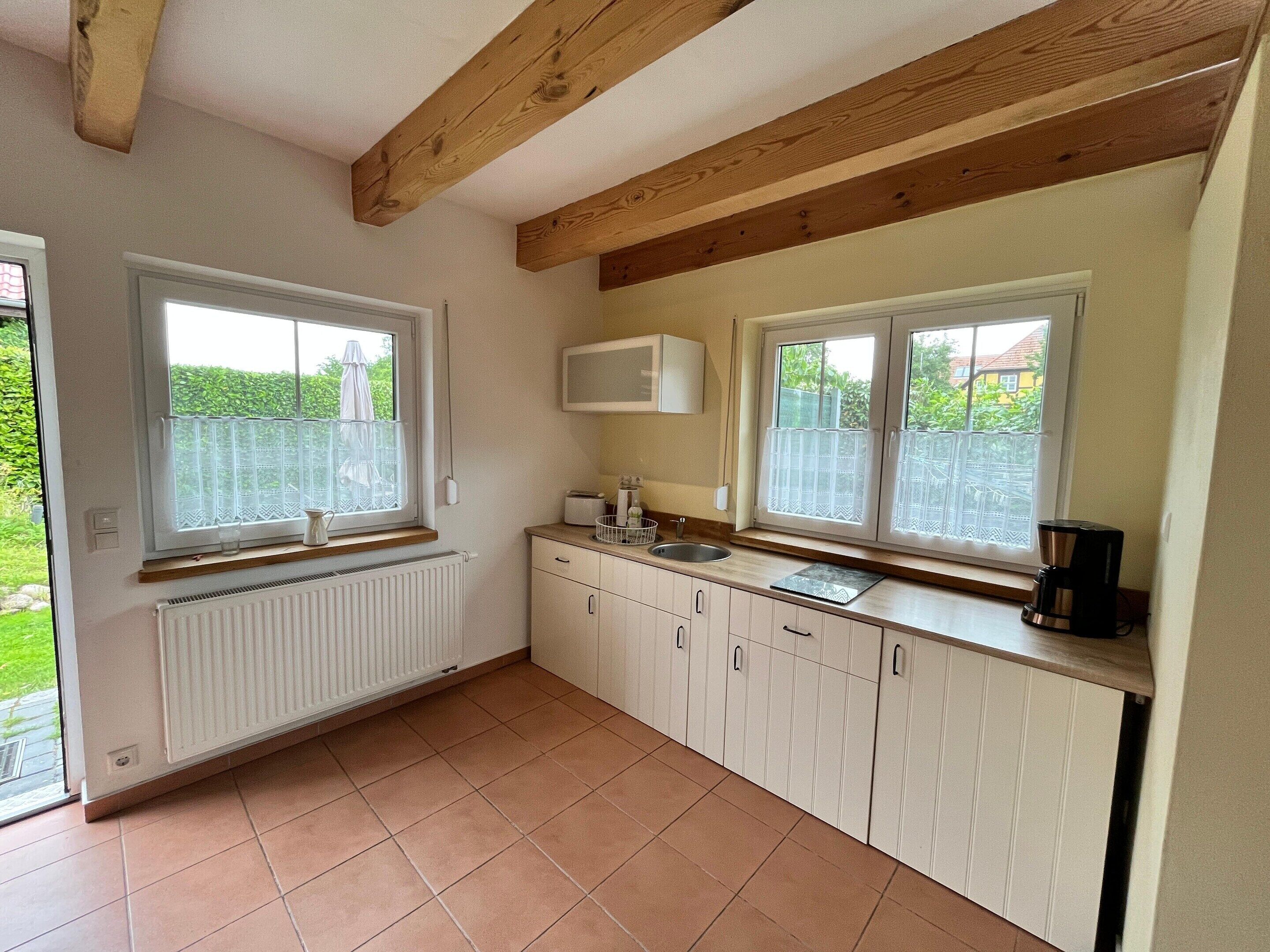 A kitchen with white cabinets, a window, a radiator, and a coffee maker.