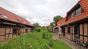A courtyard with a brick building, a garden, and outdoor seating. - Appartement fur bis zu 5 Personen im Lepels Hof (Luetow)