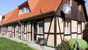 A traditional half-timbered house with a sloped red-tiled roof, a satellite dish, and a small outdoor seating area. - Appartement fur bis zu 5 Personen im Lepels Hof (Luetow)