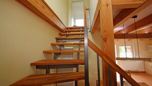 A wooden staircase with metal railings leading to a room with a window and a radiator. - Appartement fur bis zu 5 Personen im Lepels Hof (Luetow)
