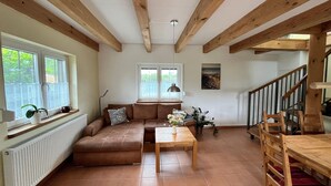 A cozy living room with a brown sofa, a wooden table, and a staircase. - Appartement fur bis zu 5 Personen im Lepels Hof (Luetow)