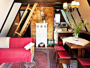 Une pièce confortable de style loft, avec un canapé rouge, une table à manger en bois et un coin cuisine.