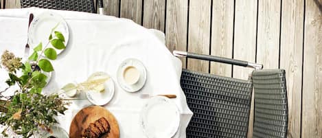 A round dining table with a white tablecloth, surrounded by wicker chairs.