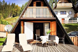 Eine Holz-A-Rohdach-Hütte mit Balkon, einem Esstisch mit Stühlen und einer Satellitenschüssel.