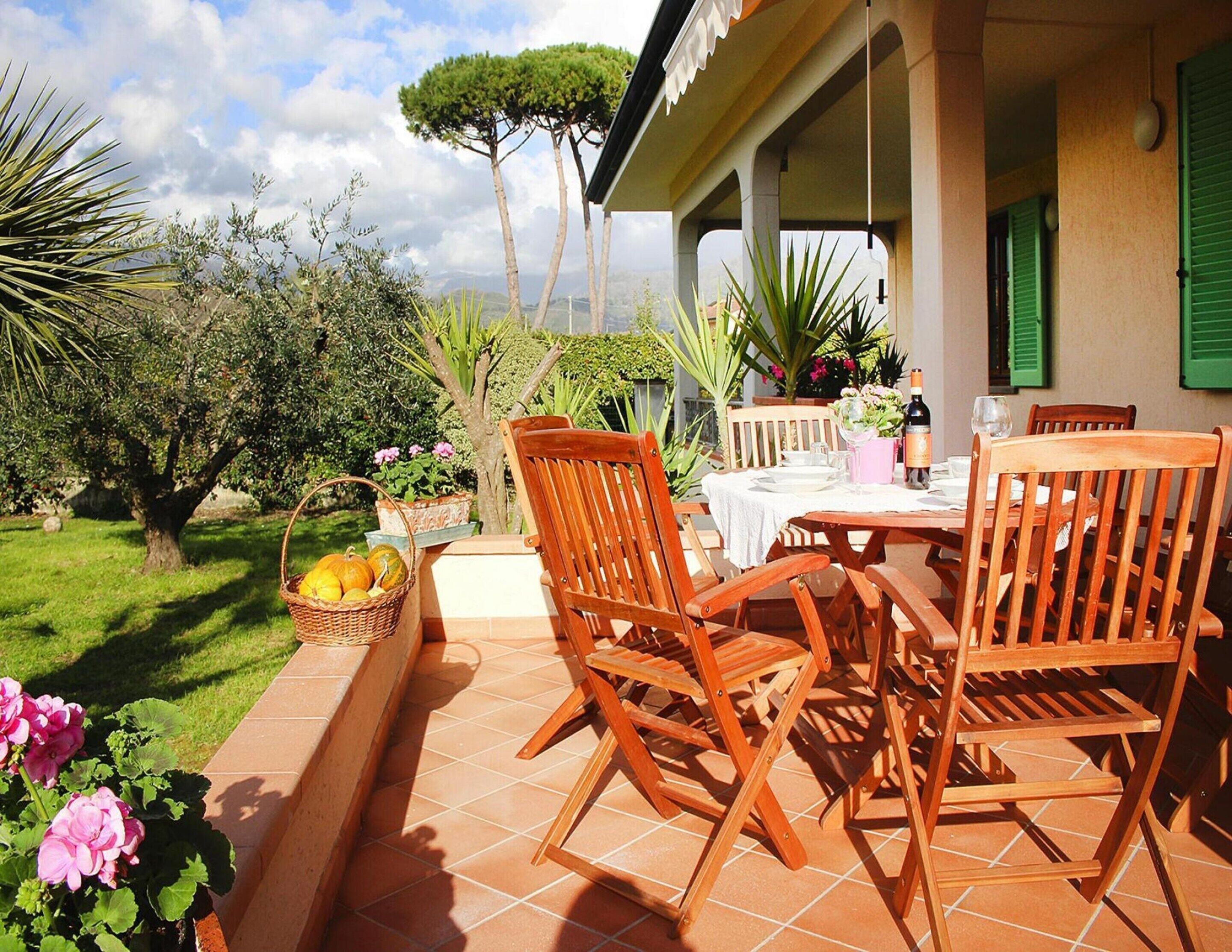 Une terrasse extérieure aménagée avec des meubles en bois et une table dressée pour les repas, entourée de verdure et offrant une vue sur la campagne.