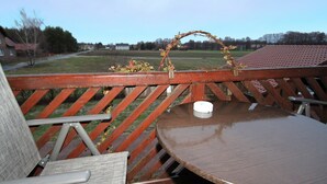 A wooden deck with a round table and chairs, a small white object on the table, and a decorative archway. - Ferienwohnungen Spreewaldperle, Alt Zauche (Alt Zauche-Wußwerk)