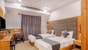 Une chambre d’hôtel avec deux lits, un bureau en bois, une chaise et un téléviseur.