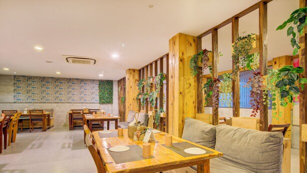 Un restaurant avec des tables et des bancs en bois, un canapé et des plantes.