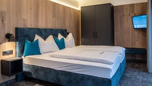 A modern bedroom with a large bed, a nightstand, a wardrobe, and a flat-screen TV mounted on the wall. - Chalet in Wald im Pinzgau Near Krimml Falls (Wald im Pinzgau)