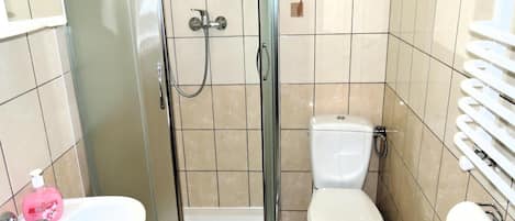 Ein Badezimmer mit Dusche, Toilette, Waschbecken und einem Händetrockner.