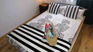 A bed with a striped bedspread, a decorative pillow, a bedside lamp, and a woven basket. - Rewal Getaway Home Near Baltic Coast (Rewal)