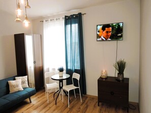 Un soggiorno moderno con un divano, un tavolo da pranzo con sedie, una TV a parete e un piccolo mobiletto.