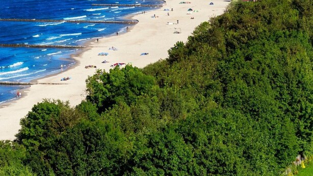A coastal beach with a sandy shore, a pier, and dense greenery. - Rewal Getaway Home Near Baltic Coast (Rewal)