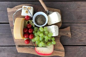 A wooden board with various cheeses, grapes, and cherry tomatoes. - Large Holiday Villa With Garden, 6 Bedrooms (Łobez)