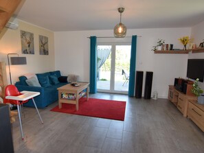 Ein Wohnzimmer mit einem blauen Sofa, einem roten Sessel, einem Couchtisch und einem Fernseher.