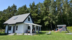 A modern house with a sloped roof, a covered porch, and a small play area with a slide. - Cottage in a Quiet Location, Slajszewo (Choczewo)