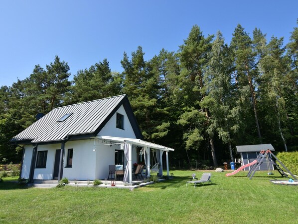 Ein modernes Haus mit Satteldach, einer Veranda und einer kleinen Spielbereitschaft inklusive Rutsche.