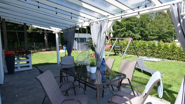 An outdoor patio with a glass enclosure, a table, and four chairs. - Cottage in a Quiet Location, Slajszewo (Choczewo)