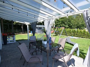 Eine Terrasse mit Glasveranda, einem Tisch und vier Stühlen.