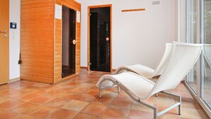 Quarto com piso de azulejos, cadeira de vime branca, portas de madeira e uma janela.