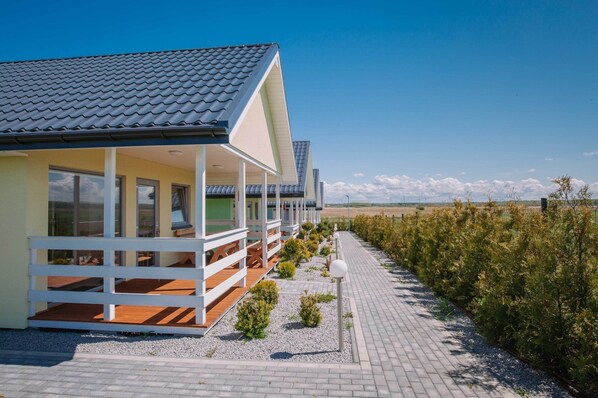 A modern building with a tiled roof, a covered porch, and a gravel pathway leading to it. - Comfortable, Single-story Houses With Terraces (Darlowo)