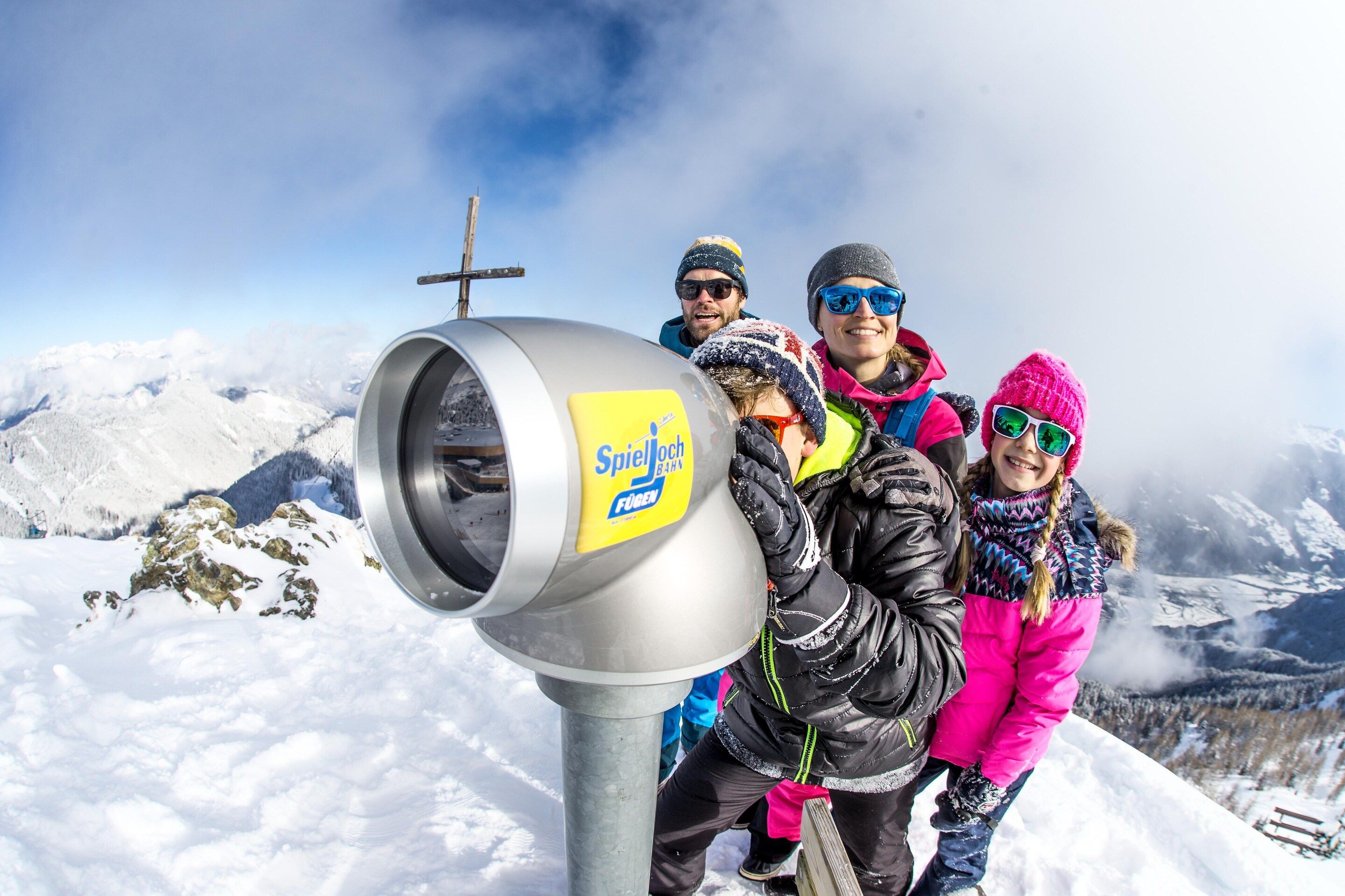 A group of people standing on a snowy mountain with a large metallic structure featuring a yellow label.